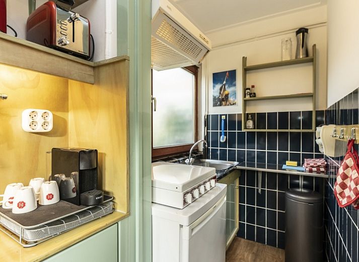 Entree van vakantiehuis Schanulleke in De Koog, Texel, Waddeneilanden met groene deur en bloeiende planten.