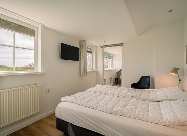 Gezellige woonkamer in De Zandhaas, vakantiehuis in De Koog, Texel, met uitzicht op de tuin en een sfeervolle houtkachel.