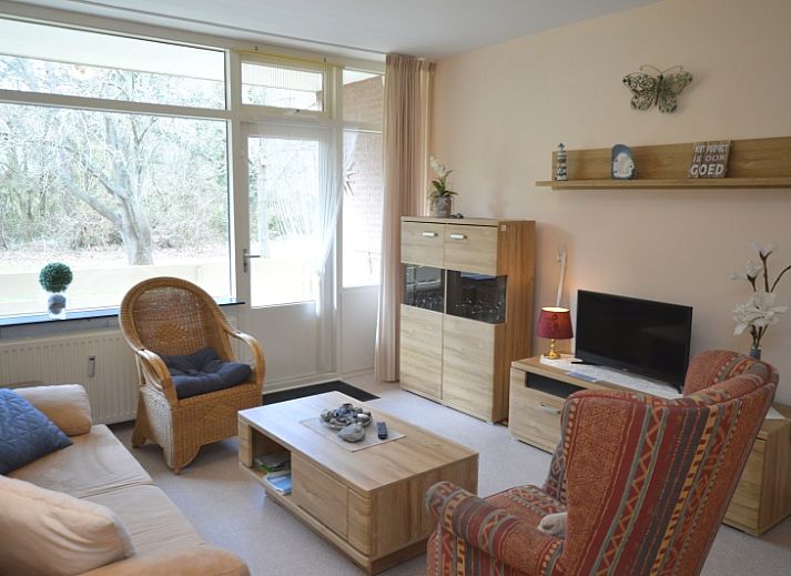 Gemuetliches Wohnzimmer des Appartements Kerckeland 68 in De Koog, Texel mit bequemer Sitzecke und Blick auf die Natur.