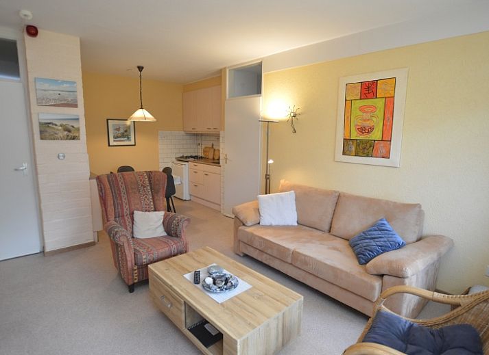 Gemuetliches Wohnzimmer des Appartements Kerckeland 68 in De Koog, Texel mit bequemer Sitzecke und Blick auf die Natur.