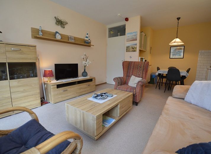 Gemuetliches Wohnzimmer des Appartements Kerckeland 68 in De Koog, Texel mit bequemer Sitzecke und Blick auf die Natur.