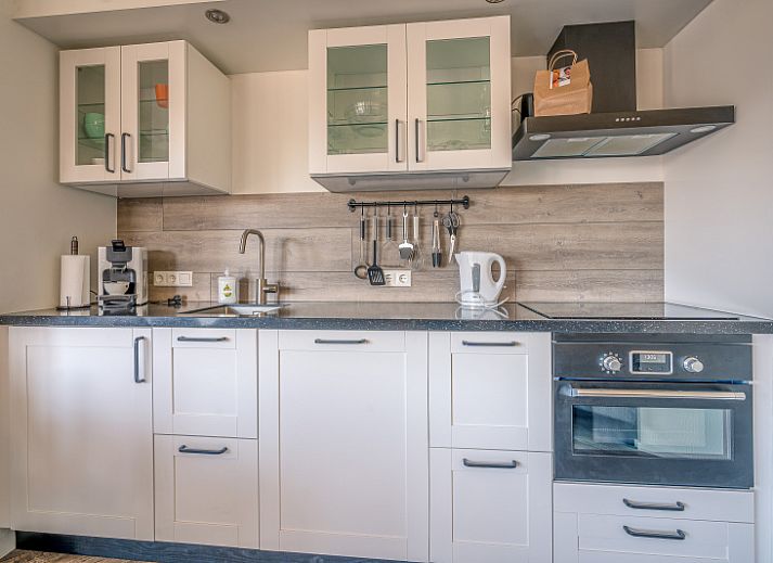 Stilvolle Einrichtung des Appartements Zeedistel 20, De Koog, Texel mit grossem Sofa und dekorativen Elementen.