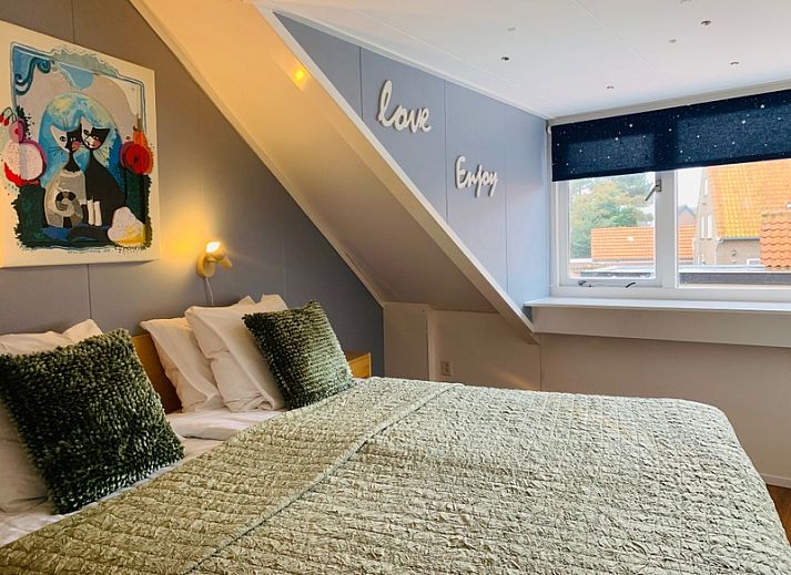 Knusse slaapkamer in Texel A, De Koog, Texel, met comfortabel tweepersoonsbed en sfeervolle verlichting onder een schuine wand.