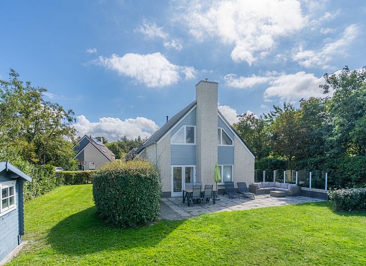 Ferienhaus Honeysuckle 59 in De Koog, Texel, umgeben von ueppiger Natur und einem ruhigen Teich.