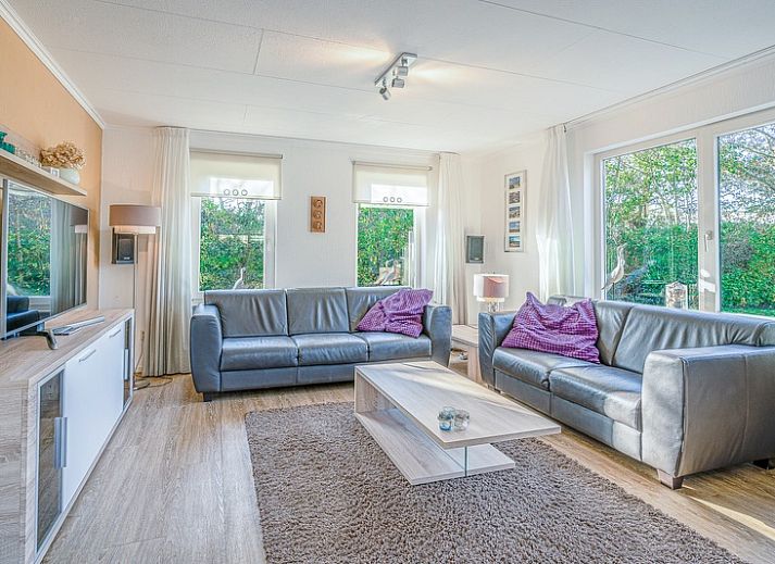 Ferienhaus Honeysuckle 59 in De Koog, Texel, umgeben von ueppiger Natur und einem ruhigen Teich.