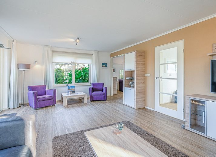 Ferienhaus Honeysuckle 59 in De Koog, Texel, umgeben von ueppiger Natur und einem ruhigen Teich.