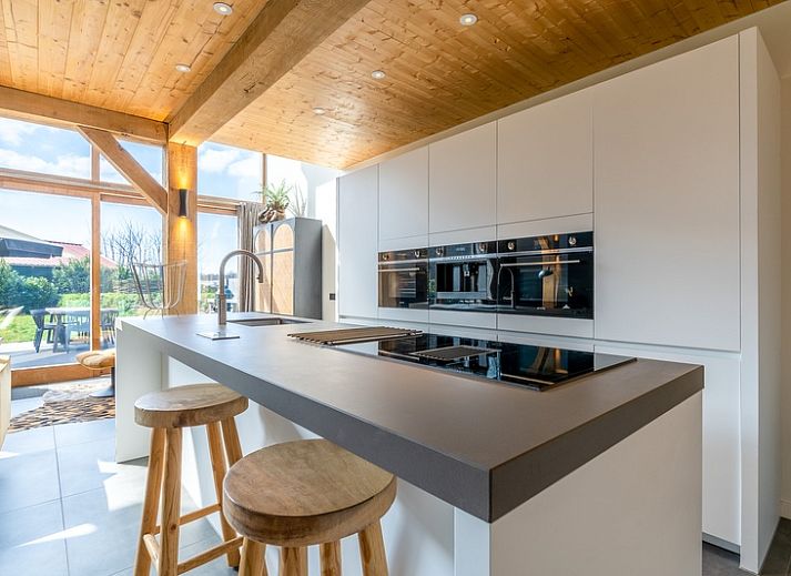 Bright living room of Villa 181 with Hot tub in De Koog, Texel with fireplace and views of the Wadden Islands green garden.