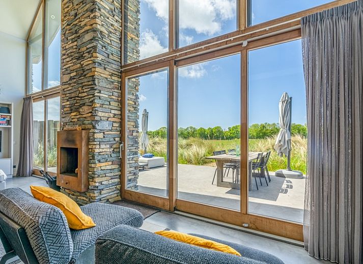 Gezellige woonkamer van Villa 193, De Koog, Texel, met open haard en uitzicht op natuur.