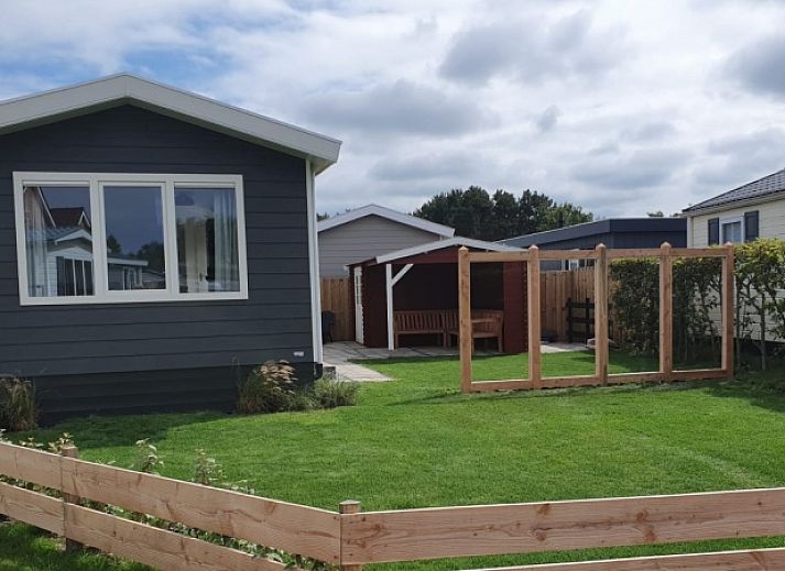 Chalet Bregkoog 154 in De Koog op Texel met groene tuin en houten hekwerk.