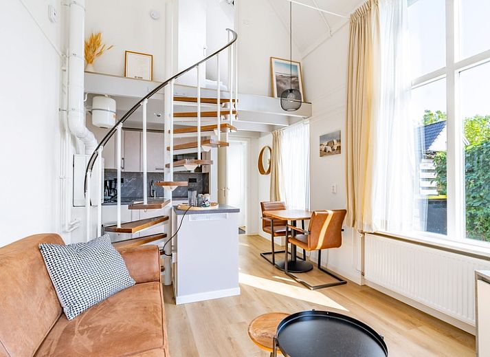 Lichte woonkamer in vakantiehuis Plevierstraat 3a, De Koog, Texel, met moderne inrichting en wenteltrap.