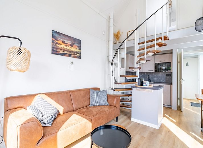 Lichte woonkamer in vakantiehuis Plevierstraat 3a, De Koog, Texel, met moderne inrichting en wenteltrap.