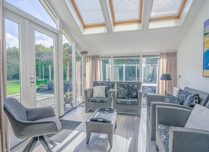 Achteraanzicht van Vakantiehuis Kamperfoelie 83 met sauna in De Koog Texel, omgeven door groen.