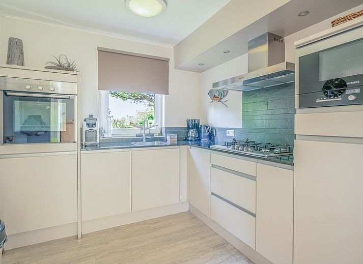 Achteraanzicht van Vakantiehuis Kamperfoelie 83 met sauna in De Koog Texel, omgeven door groen.