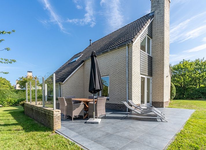 Geraeumige Terrasse im Ferienhaus Kamperfoelie 85 in De Koog, Texel mit bequemen Liegestuehlen und Esstisch.