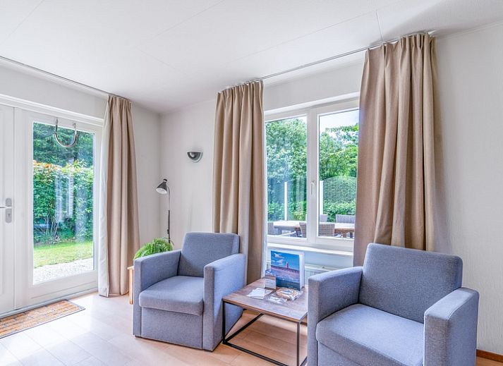 Sonnige Terrasse des Ferienhauses Honeysuckle 85 in De Koog, Texel mit Sonnenschirm und Gartenmoebeln.