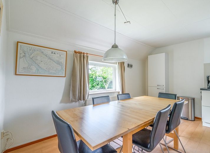 Sonnige Terrasse des Ferienhauses Honeysuckle 85 in De Koog, Texel mit Sonnenschirm und Gartenmoebeln.