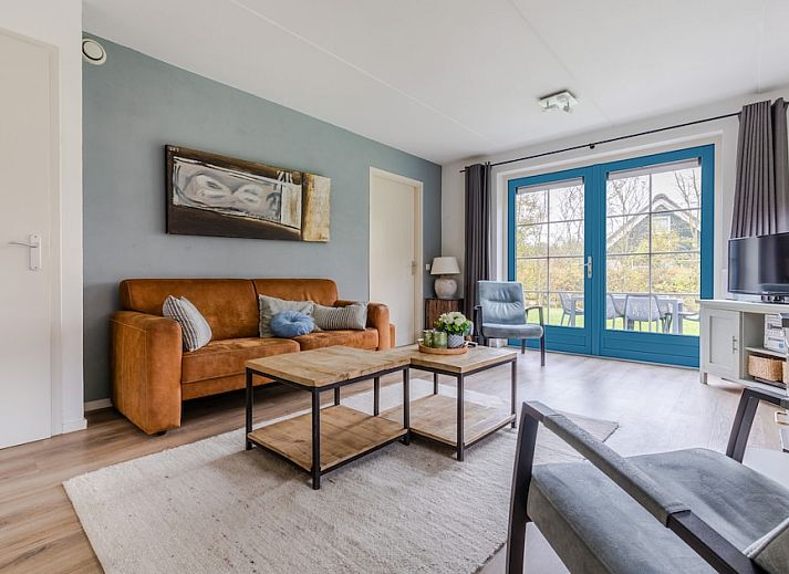 T6AB Komfort-Bungalow in De Koog, Texel mit blauen Fensterlaeden und roten Dachziegeln, umgeben von gruener Natur und ruhiger Umgebung.