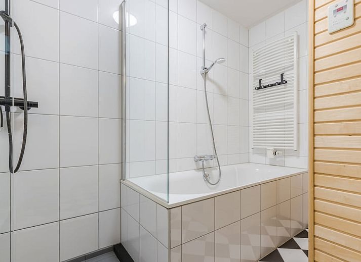 T6AB Komfort-Bungalow in De Koog, Texel mit blauen Fensterlaeden und roten Dachziegeln, umgeben von gruener Natur und ruhiger Umgebung.