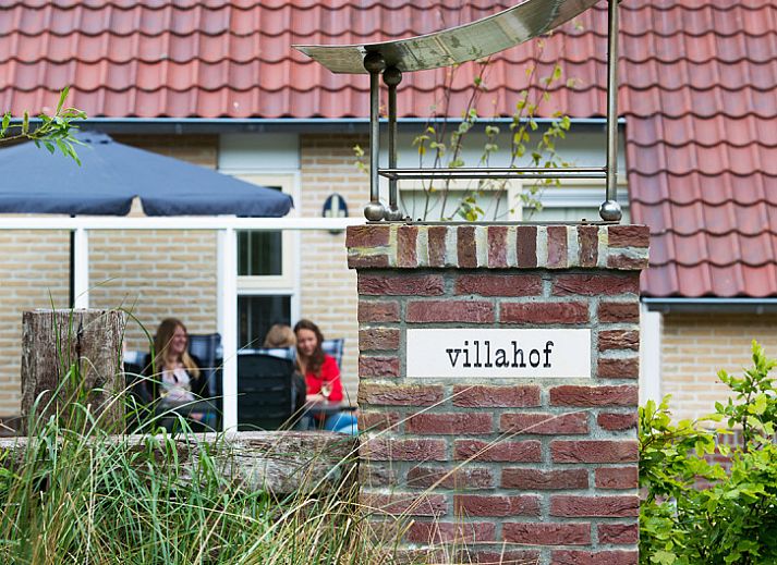 Villa 1 in De Koog, Texel biedt een zonnig terras met comfortabele zitplaatsen in een groene omgeving.