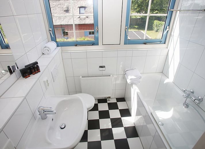 Gezellige woonkamer in T8A bungalow, De Koog, Texel met comfortabele rode bank en veel natuurlijk licht, perfect voor ontspanning.