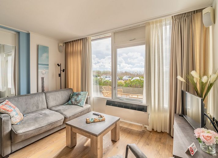 Gezellige woonkamer in Appartement Juliana 076 Eilandzicht, De Koog, Texel met uitzicht op terras en natuur.