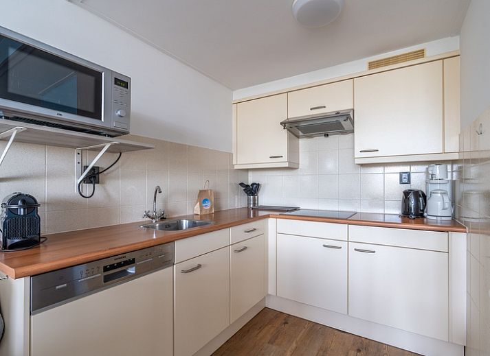 Lichte leefruimte van Appartement Juliana 076 Eilandzicht in De Koog, Texel met comfortabele zithoek en buitenzicht.