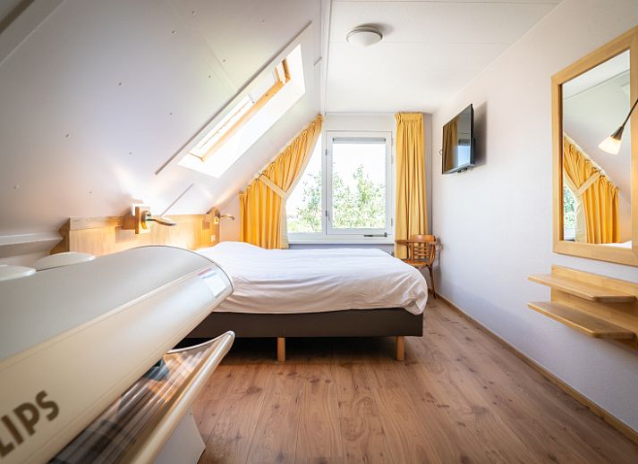 Gezellige woonkamer van Villa 4 personen in De Koog Texel, met comfortabele stoelen en kleurrijke kunst aan de muur.