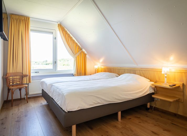 Gezellige woonkamer van Villa 4 personen in De Koog Texel, met comfortabele stoelen en kleurrijke kunst aan de muur.