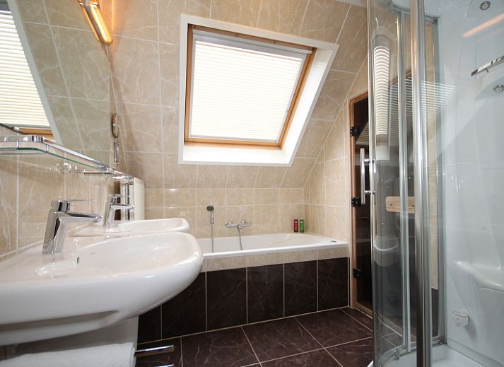 Gezellige woonkamer van Villa 4 personen in De Koog Texel, met comfortabele stoelen en kleurrijke kunst aan de muur.