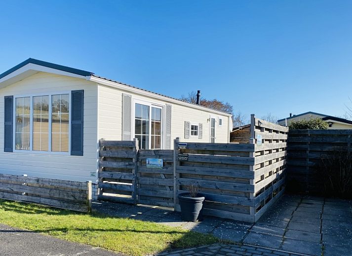 Chalet Bregkoog 255 in De Koog, Texel met houten omheining en zonnige buitenkant.