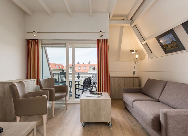 Gezellige woonkamer van C Appartement Comfort 4 in De Koog, Texel, met uitzicht op het terras en moderne inrichting.