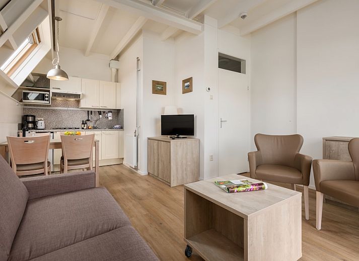Gezellige woonkamer van C Appartement Comfort 4 in De Koog, Texel, met uitzicht op het terras en moderne inrichting.