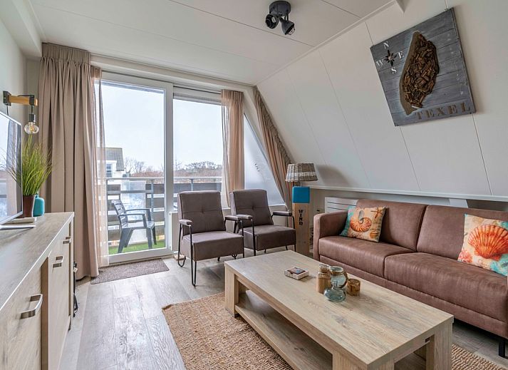 Gezellige woonkamer van Appartement Anna 224 in De Koog, Texel met comfortabele zithoek en balkonzicht.