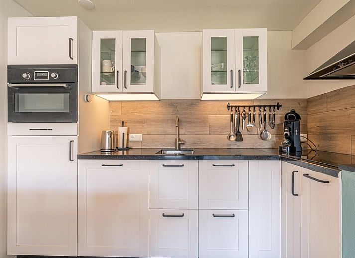 Stijlvolle zithoek in Appartement Anna 220, De Koog, Texel met comfortabele stoelen en een flatscreen-tv.