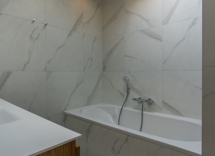 Zijaanzicht van vakantiehuis 16 - Zeebries in De Koog, Texel, omgeven door groen op de Waddeneilanden.