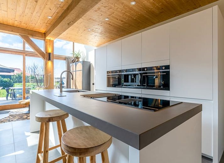 Gezellige woonkamer met open haard in Vakantiehuisje in De Koog, Texel, omringd door natuur.