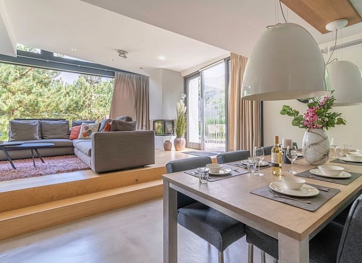 Gemuetliches Wohnzimmer im Ferienhaus in De Koog, Texel, mit grossen Fenstern und Blick auf die Natur, perfekt fuer Entspannung auf den Watteninseln.