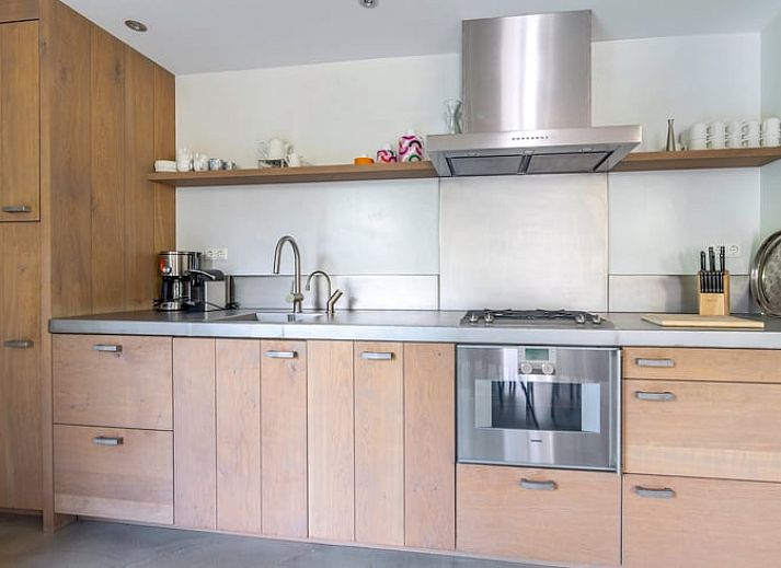 Gemuetliches Wohnzimmer im Ferienhaus in De Koog, Texel, mit grossen Fenstern und Blick auf die Natur, perfekt fuer Entspannung auf den Watteninseln.