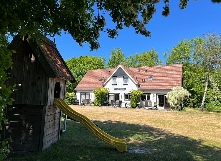 Gemuetliches Wohnzimmer von Landgoed Springtij - Koetshuis 1, De Koog, Texel, mit bequemen Sitzgelegenheiten und Tageslicht.