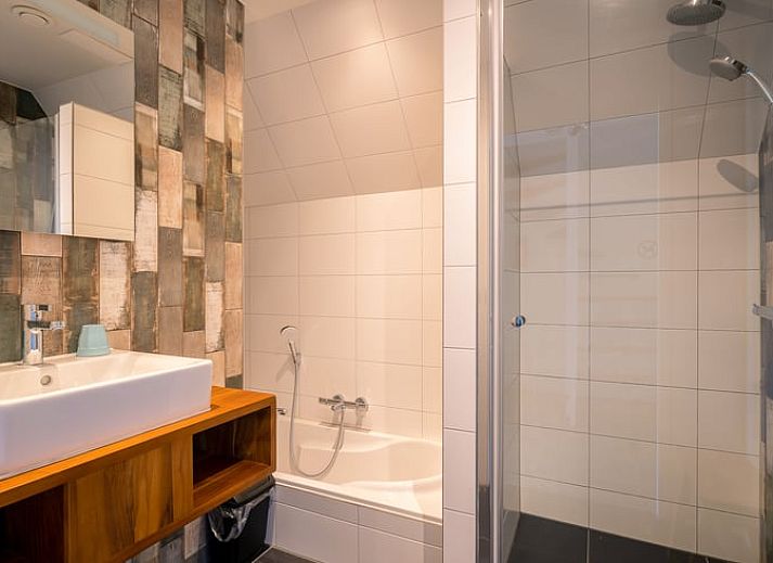 Cozy sitting area in Holiday Home in De Waal, Texel with flat-screen TV and atmospheric lighting.