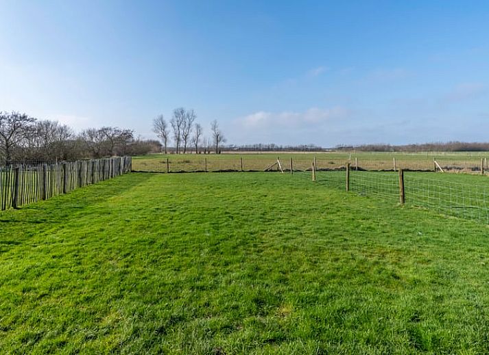 Cozy sitting area in Holiday Home in De Waal, Texel with flat-screen TV and atmospheric lighting.