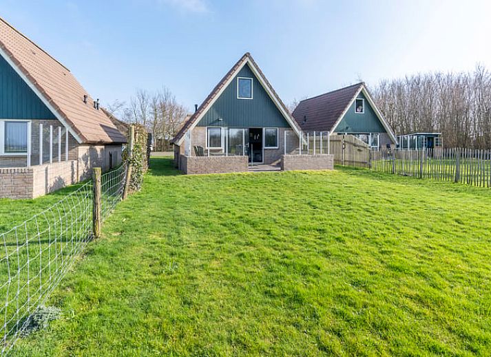 Cozy sitting area in Holiday Home in De Waal, Texel with flat-screen TV and atmospheric lighting.