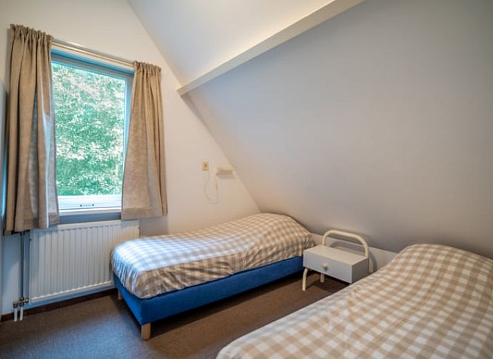 Ruime zitkamer in Huisje in De Waal, Texel met uitzicht op de tuin en toegang tot het terras.