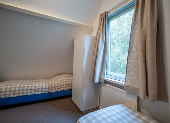 Ruime zitkamer in Huisje in De Waal, Texel met uitzicht op de tuin en toegang tot het terras.