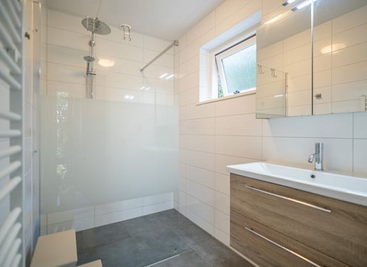 Ruime zitkamer in Huisje in De Waal, Texel met uitzicht op de tuin en toegang tot het terras.