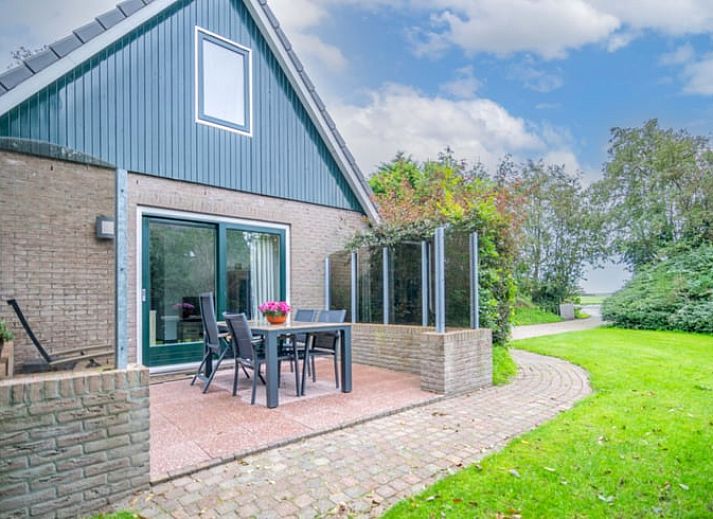 Ruime zitkamer in Huisje in De Waal, Texel met uitzicht op de tuin en toegang tot het terras.