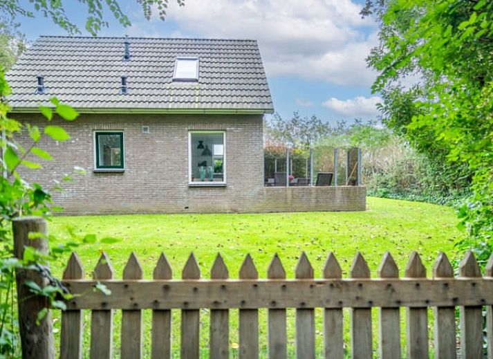 Ruime zitkamer in Huisje in De Waal, Texel met uitzicht op de tuin en toegang tot het terras.