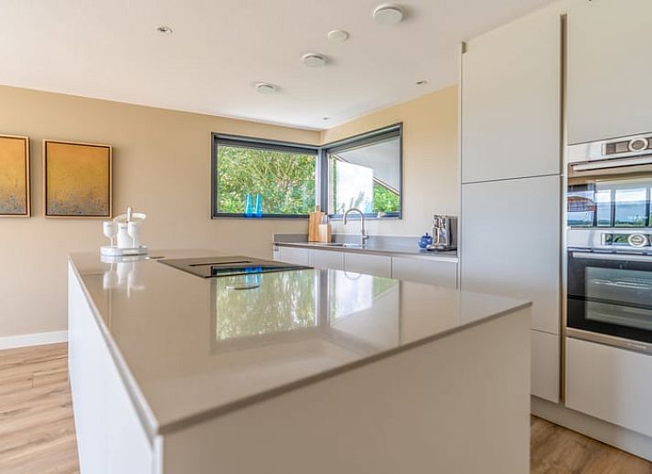 Lichte woonkamer in Vakantiehuisje in De Waal, Texel met moderne inrichting en uitzicht op de tuin.