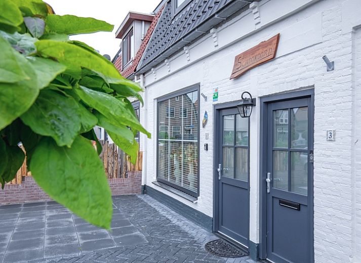 Vorderansicht des Ferienhauses Schoonoord in Den Burg, Texel mit gruener Umgebung.
