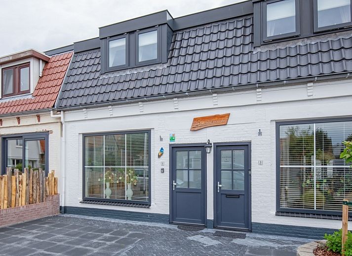 Vorderansicht des Ferienhauses Schoonoord in Den Burg, Texel mit gruener Umgebung.